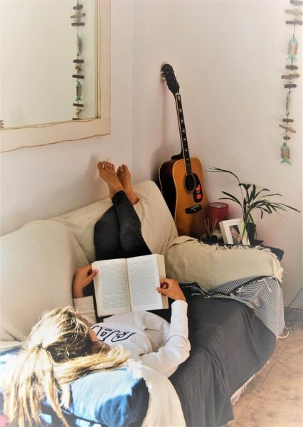 Frau liest Buch auf Sofa.
