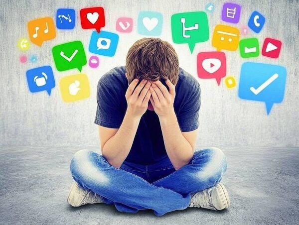 Junger Mann mit Stress durch Medien